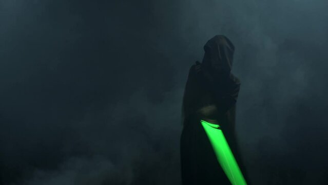 Young man in cosplay costume with lightsaber battle on black background in smoke and rain, 4k slow motion video filmed on 8k camera nikon z9