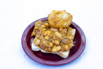 Traditional South African potjie kos prepared on an open fire in a cast iron pot on a piece of toast as a snack