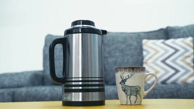 Vacuum Flask And Coffee Mug On Center Table In The Living Room. closeup shot