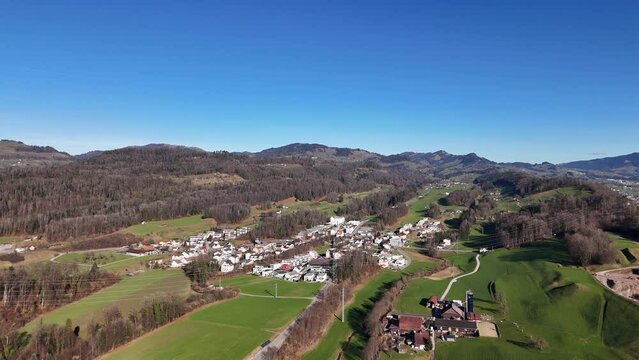 Rural Swiss Village Eschenbach during sunny day with blue sky. Swiss idyllic neighborhood. Aerial forward flight.