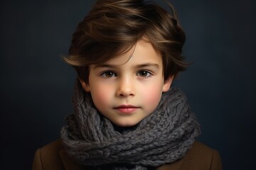 Portrait of a little boy in a brown coat and gray scarf.