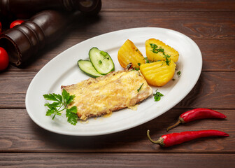 Fried fish with boiled potatoes. On a wooden background.