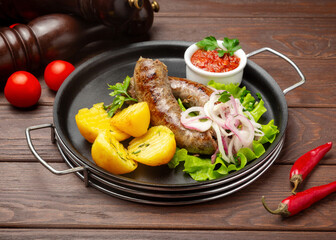 Fried meat sausage with boiled potatoes. On a wooden background.