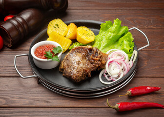 Beef kazan kebab with boiled potatoes. On a wooden background.