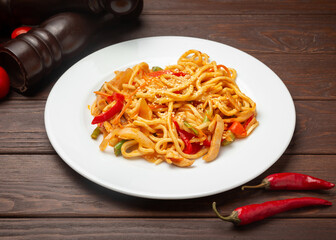 Wok noodles with chicken. On a wooden background.
