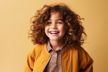 Portrait of a beautiful little girl with curly hair over yellow background