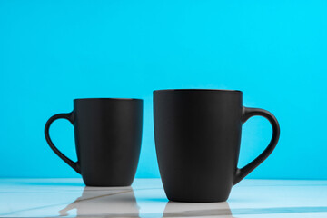 Two ceramic mugs on blue studio background