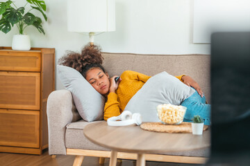 African American teenage women sitting on sofa listening to music enjoying meditation for sleep and peaceful mind in wireless headphones relax at home.