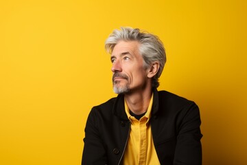 Handsome senior man with gray hair and beard on yellow background