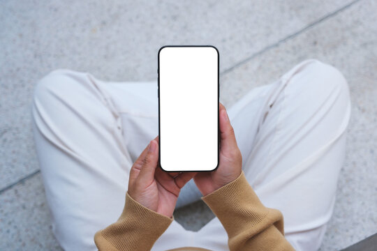 Top view mockup image of a woman holding mobile phone with blank desktop white screen