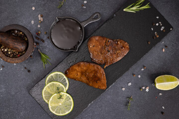 pieces of Organic grilled Tuna Steak on black stone serving board and teriyaki soy sauce