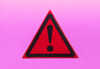 A warning sign in a red triangle on a colored background in close-up