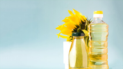 A banner of sunflower oil in transparent bottles and a sunflower flower in close-up on a blue background