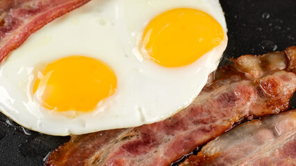 Cooking bacon and eggs on pan