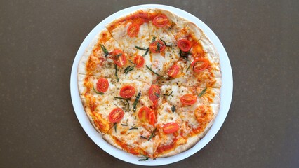 A California style pizza with tomatoes and cheese served on a white plate atop a table