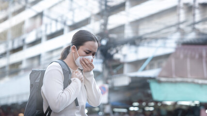 Sick young woman wears a mask to protect against PM 2.5 dust coming from the city and air...
