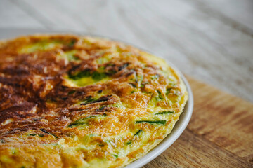 Asparagus omelet on wooden table with space for text.