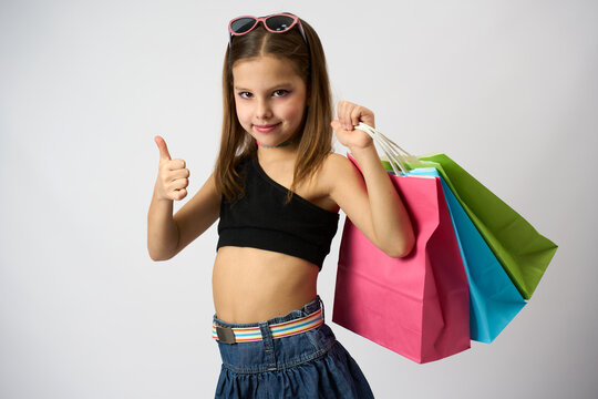 Portrait of a cute girl with colorful shopping bags showing thumbs up gesture