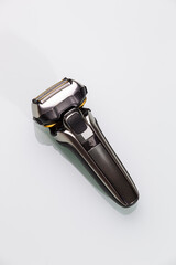 Lifestyle Ideas. Closeup of Black Modern Stylish Electric Mens Washable Shaver on White Reflective Surface.