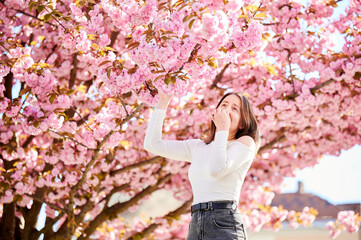 Woman allergic suffering from seasonal allergy at spring in blossoming garden at springtime. Young...