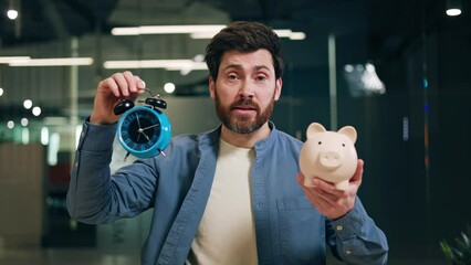 Successful finance adviser making speech while looking at camera with alarm clock and piggy money box in hands. Confident investor recommending business building strategy. Time is money concept.
