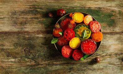 Ripe, delicious tomatoes cut in half on a plate on a dark wooden background with a place for text.