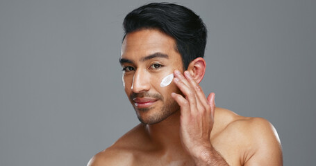 Face, cream and man with skincare, cosmetics and dermatology on a grey studio background. Portrait,...