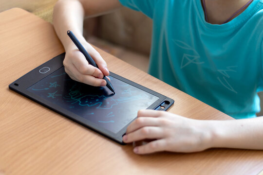 An unrecognizable boy draws with stylus on graphics tablet on theme of space. close-up