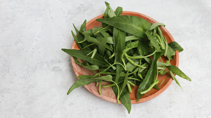 Water spinach or Kangkung on wooden plate isolated on grey background. food preparation