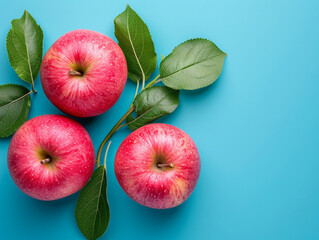 Red apples with leaves on a blue background.