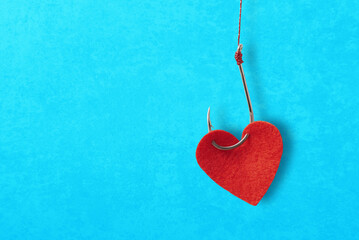 The heart and the fishing hook on blue background with copy space