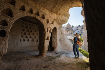 Woman traveling in Cappadocia, standing inside the cave with the view of the pigeon valley in Turkey