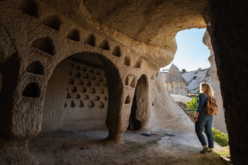 Woman travelling in Cappadocia, standing inside the cave with the view of the pigeon valley in...