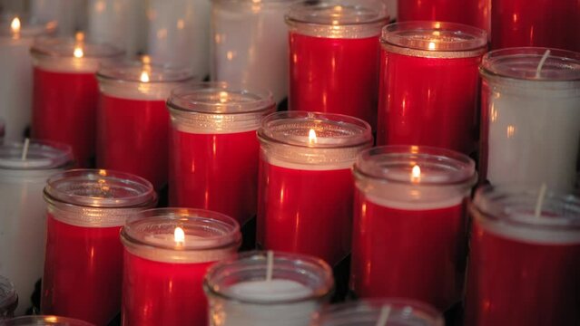 A bunch of red and white candles are lit up in a row