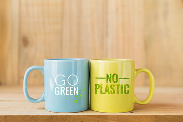 Go green and No plastic logo on coffee mug with space on blurred wood background, ecological product