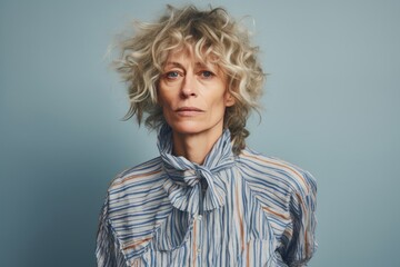 Portrait of mature woman with blond curly hair, studio shot.