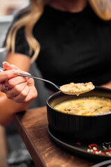 woman eating vegetable fish cream soup in bowl at cafe or restaurant