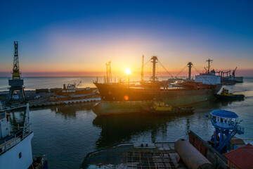 Sunrise bustling sea port, cargo ships docked at berth, cranes poised for unloading. Logistics hub...