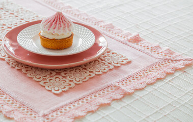 white and pink cupcake on plate on table