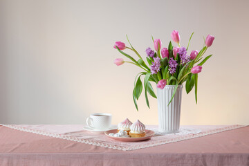 cup of tea and cupcakes with spring flowers in light colors