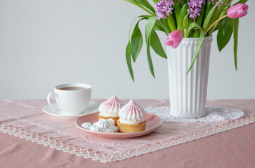 cup of tea and cupcakes with spring flowers in light colors