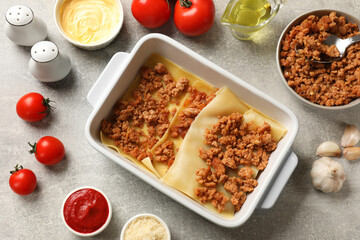 Cooking lasagna. Pasta sheets, minced meat in baking tray and products on light textured table, flat lay