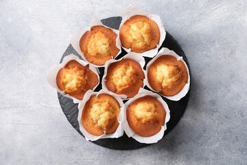 Delicious sweet muffins on light grey textured table, top view