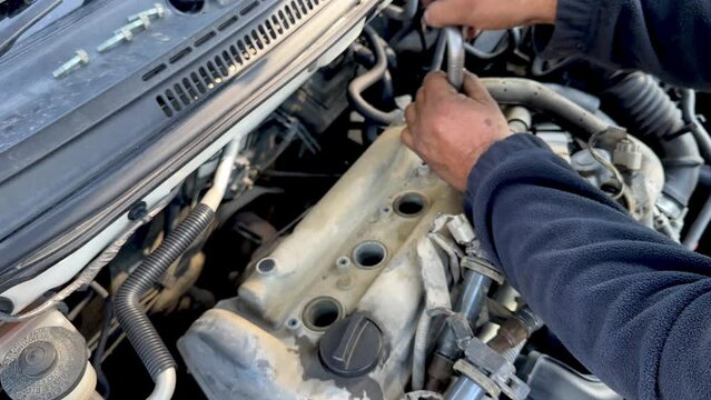 Close up of a mechanic man's hands tightening the spark plug of an engine