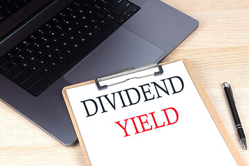 DIVIDEND YIELD text written on a paper clipboard on laptop