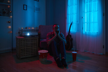 Man enjoying popcorn and juice while watching movie at home projector.