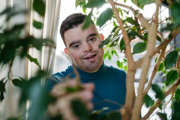 Portrait of young man with Down syndrome in the middle of indoor plants.