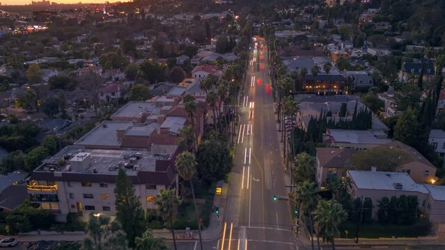 Evening traffic at busy street intersection on Hollywood Boulevard in Los Angeles, California at dusk.  Hollywood Hills in background. Aerial hyperlapse timelapse view.
