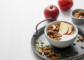 Healthy breakfast. Homemade granola or muesli with apple and nuts in a bowl on a white background.