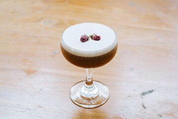 Coffee Cocktail with frothy top and dried rose buds